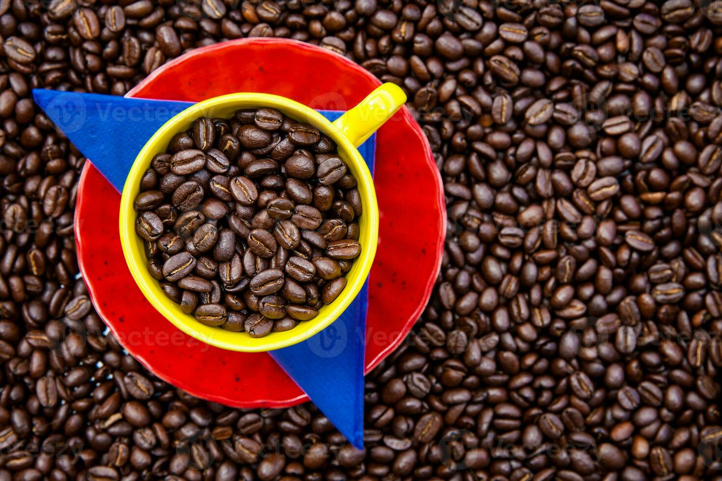 Cup filled with Colombian coffee beans and the colors of the Colombian flag over a background of roasted coffee beans photo