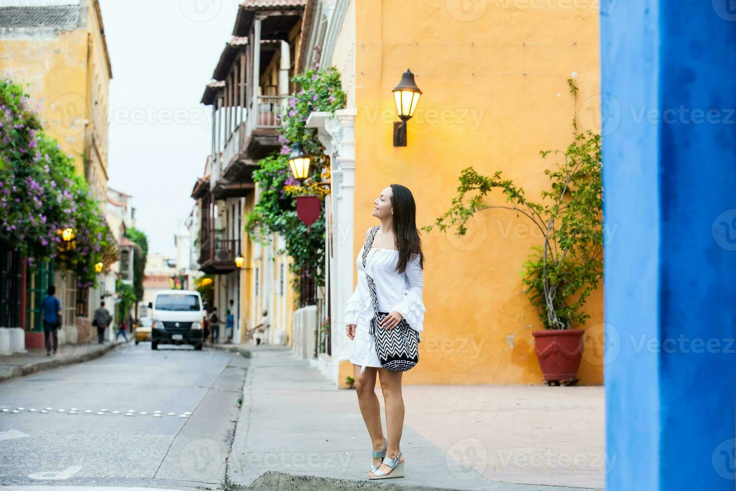 Beautiful woman on white dress walking alone at the colorful streets of the colonial walled city of Cartagena de Indias photo