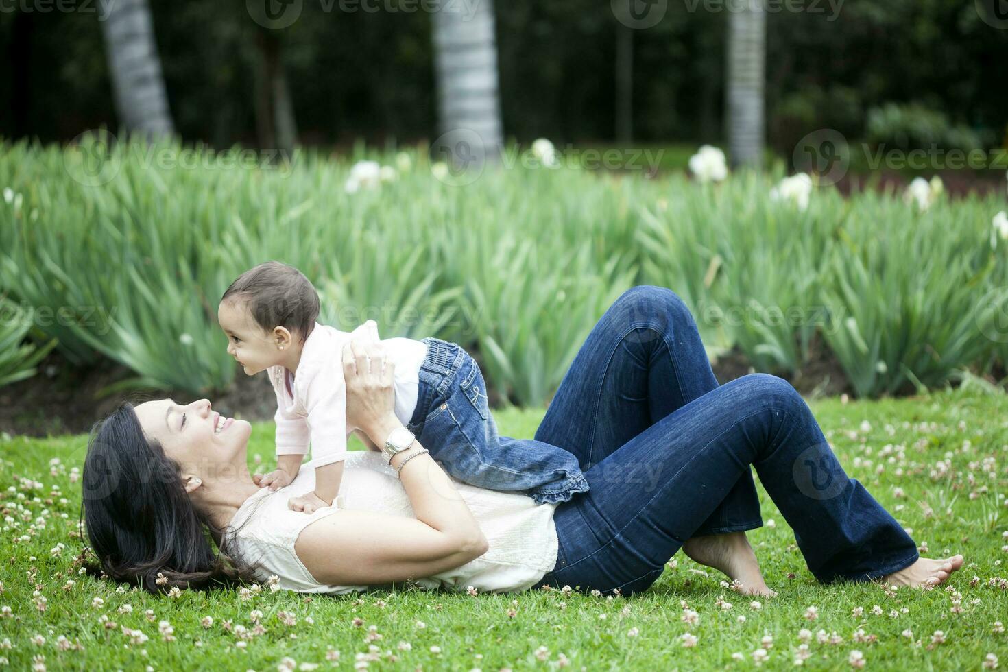 bebé niña jugando con su mamá en el césped foto