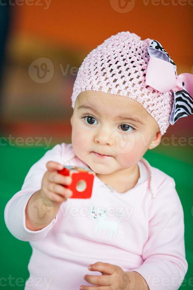 Portrait of a beautiful nine months baby playing on a colorful background. Learning concept photo