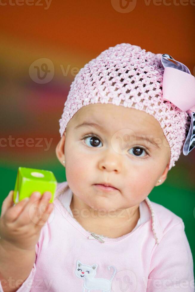 Portrait of a beautiful nine months baby playing on a colorful background. Learning concept photo