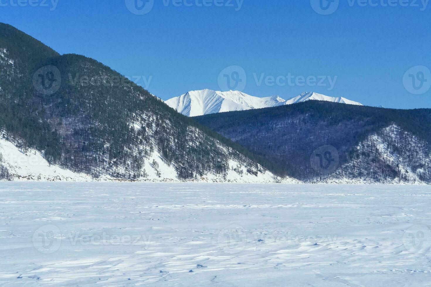 Baikal mountains in winter in snow. Forest in snow covered mount photo