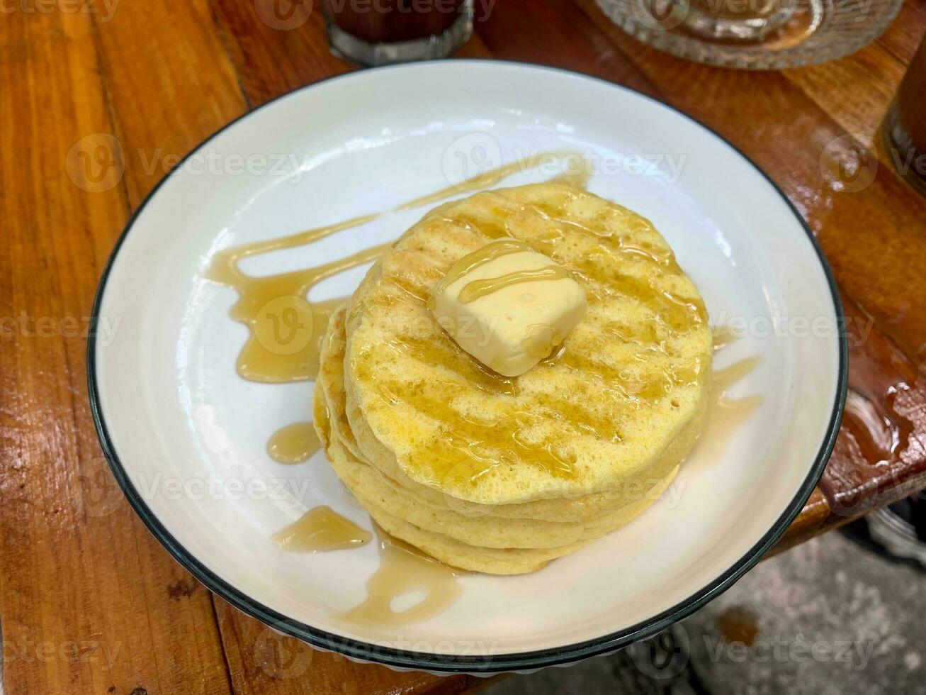 Stack of plain pancakes with butter and honey on a white plateStack of plain pancakes with butter and honey on a white plate photo