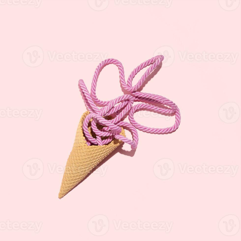 Pastel pink fabric cord in an ice cream cone, creative summer holiday concept, melting fruit flavor cream idea, stylish nautical cord. photo