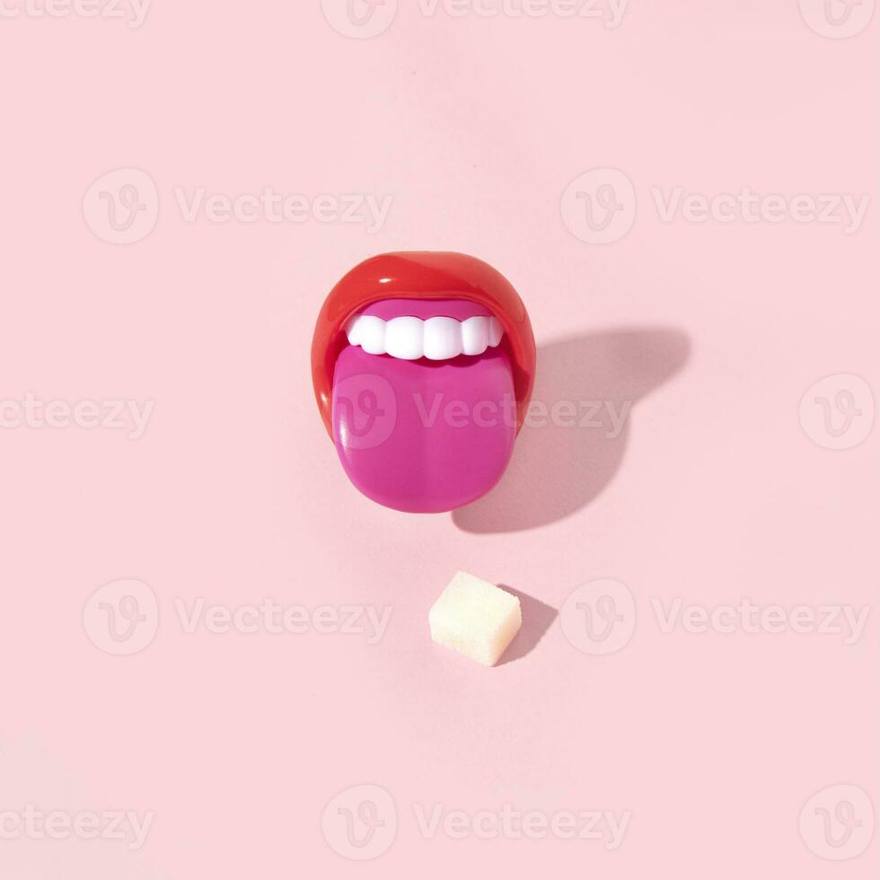 A tongue sticking out and a sugar cube, creative layout, pastel pink background. photo