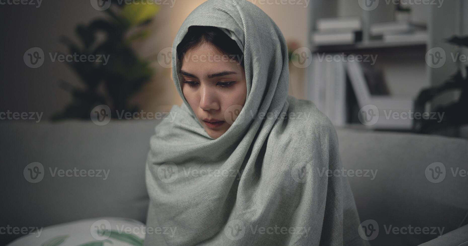 asiático joven mujer sentado debajo cobija con sufrimiento desde frío y gripe a hogar foto