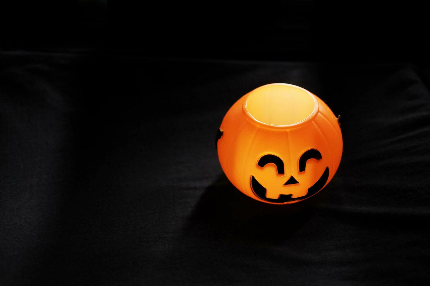 Smiling Halloween pumpkin head on black clothes in natural shadow and sunlight. Halloween holiday concept. photo