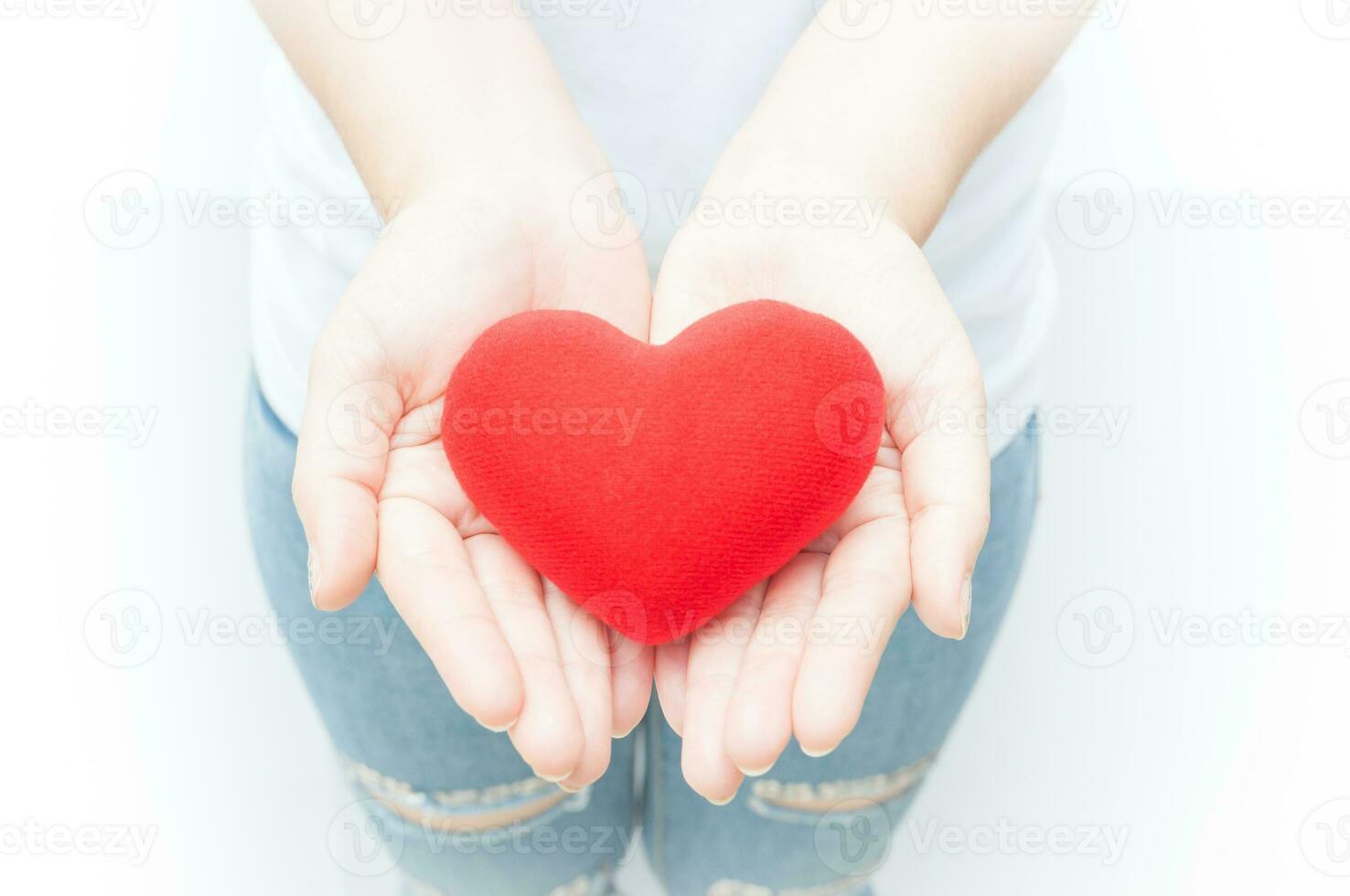 Woman holding and protecting give a red heart shape on white background close-up,Symbol of love or dating Valentines day photo