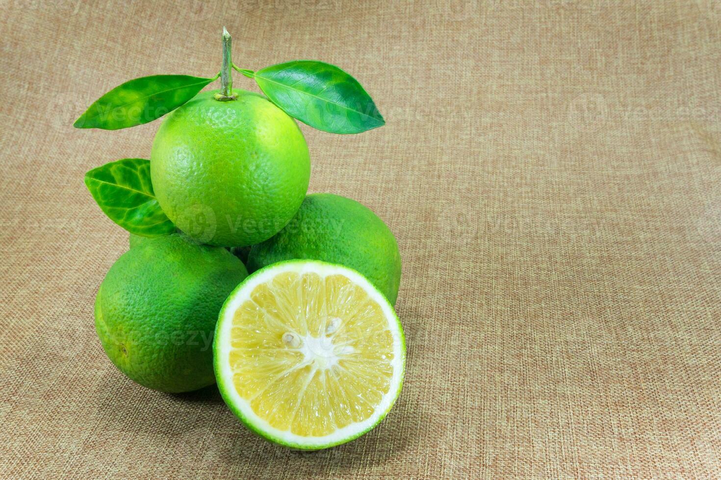 agrios fruta, composición con hojas en marrón tela antecedentes foto