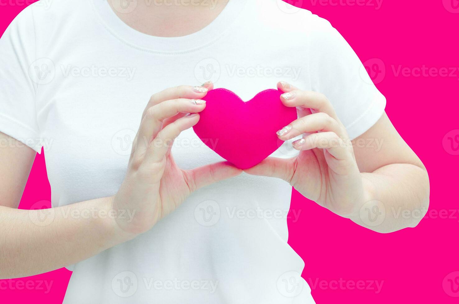 Woman hand holding plush a red heart at left her chest on pink background ,Valentine day concept ,Love heart, protect and healthcare photo