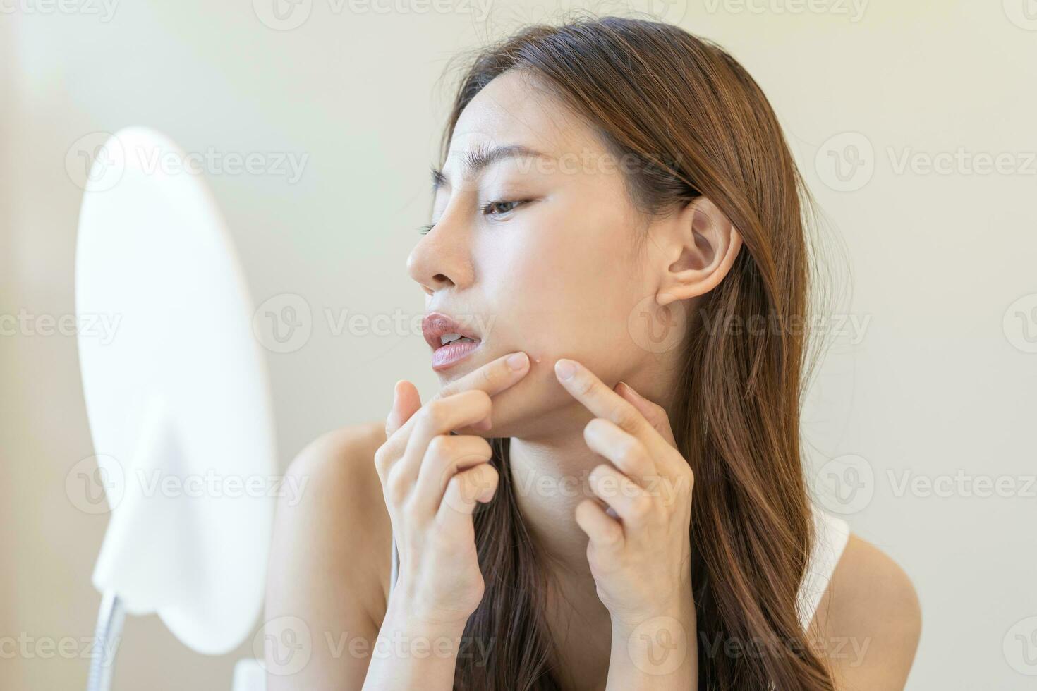 Dermatology, puberty asian young woman, girl looking into mirror, allergy when wear mask and cosmetic, show squeezing pimple spot for removing from face.Beauty care from skin problem by acne treatment photo