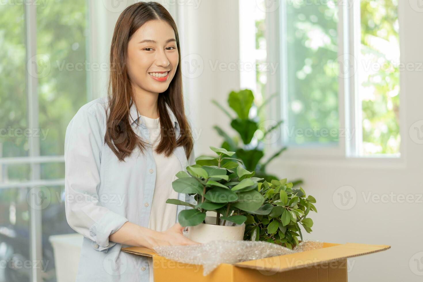 Happy asian young woman, customer received, unpack package carton open parcel in cardboard box, holding ceramic plant pot. Moving, preparing in new house, relocation. Online shop delivery at home. photo
