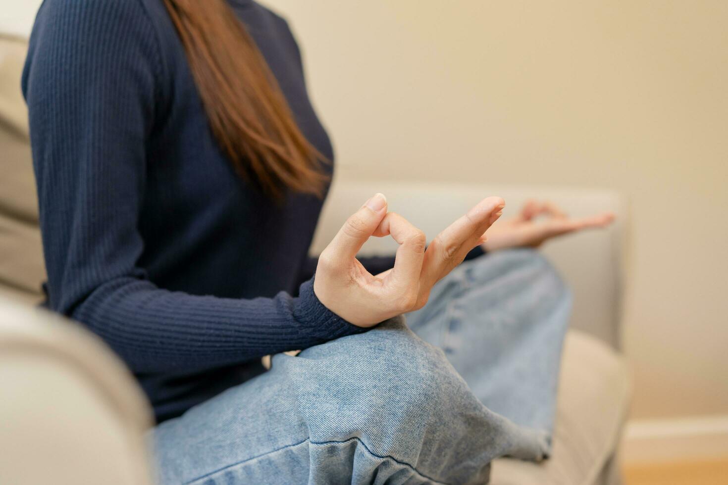 Close up hands of calm pose asian young woman, girl practice sitting, meditating in lotus position on sofa at home, meditation, exercise for wellbeing, healthy care. Relaxation, leisure people. photo
