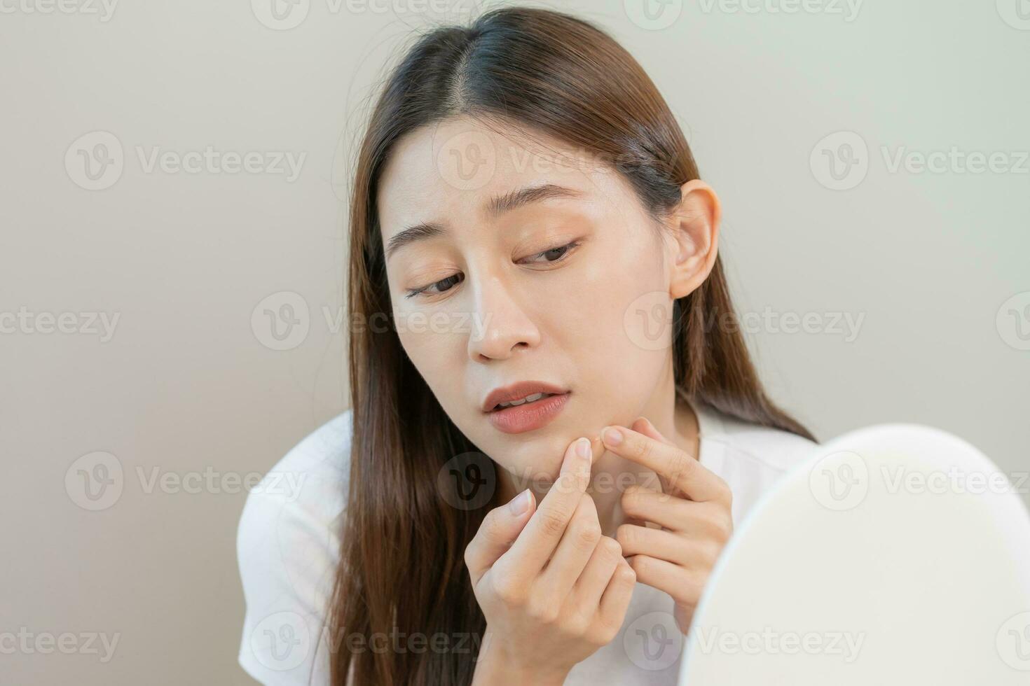 Dermatology, puberty asian young woman, girl looking into mirror, allergy when wear mask and cosmetic, show squeezing pimple spot for removing from face.Beauty care from skin problem by acne treatment photo