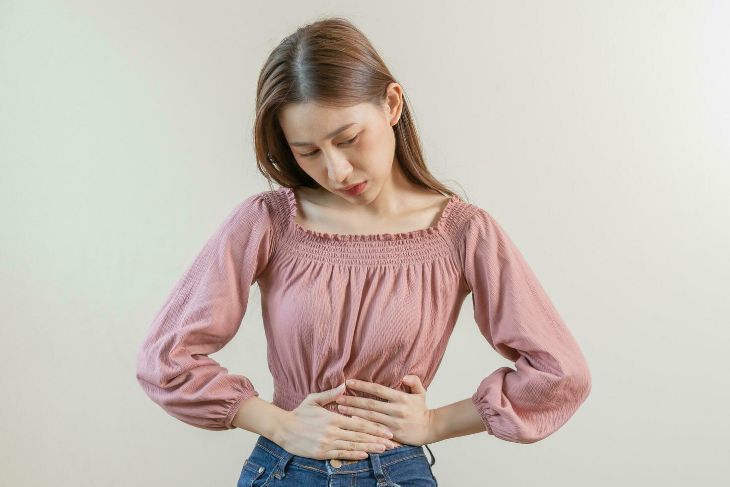 flatulencia joven asiático mujer, niña mano en estómago dolor, sufrir desde comida envenenamiento, abdominal dolor y colon problema, gastritis o diarrea. paciente barriga, abdomen o inflamación, concepto. foto