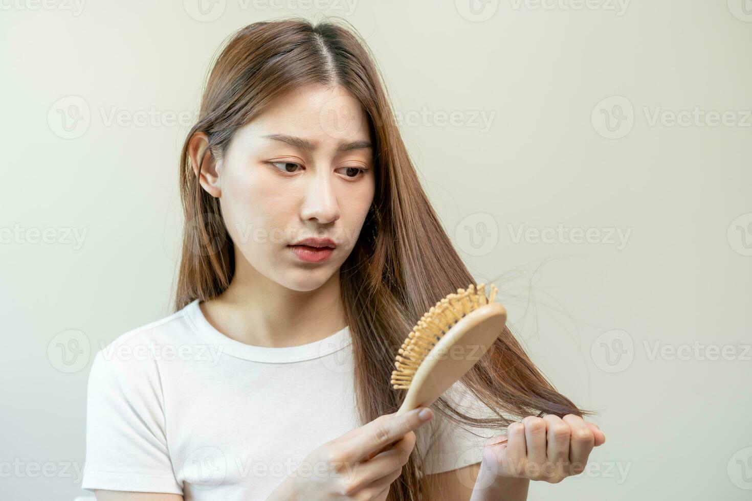 grave, preocupado asiático joven mujer, niña participación peine, espectáculo su cepillo para el pelo con largo pérdida pelo problema después cepillado, pelo otoño fuera problema. salud cuidado, belleza con Copiar espacio en blanco antecedentes. foto