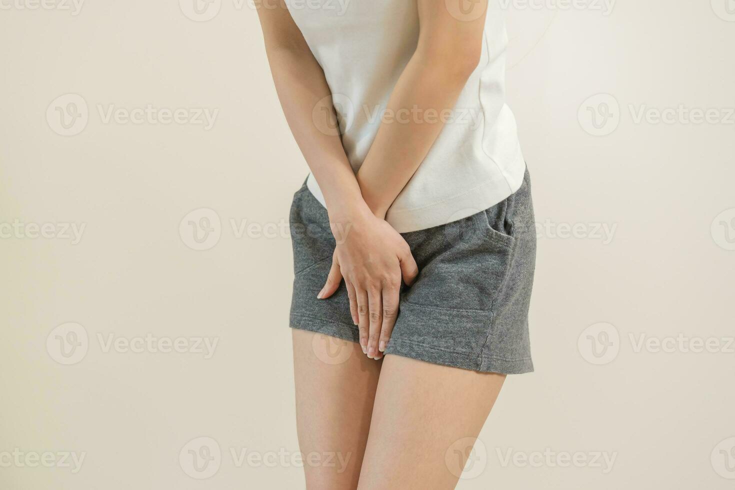 Young woman on her bed with both hands pressed to her stomach