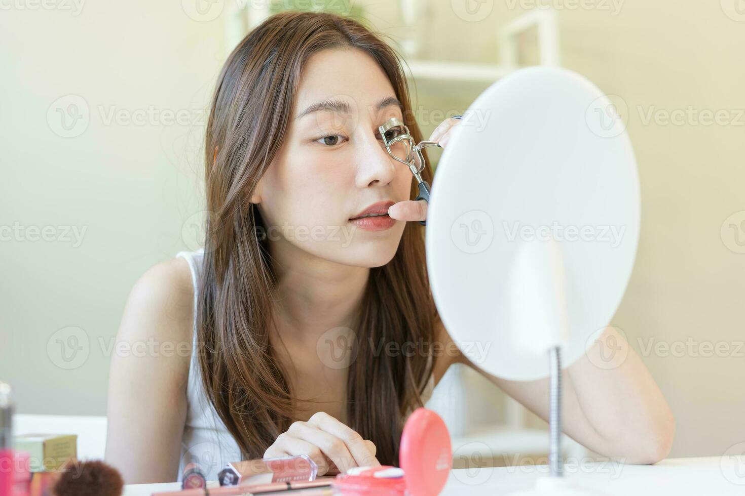 Happy beauty concept, asian young woman, girl make up face hand using eyelash curler on long eyelash before applying mascara brush, looking mirror in morning routine. People look with natural fashion. photo