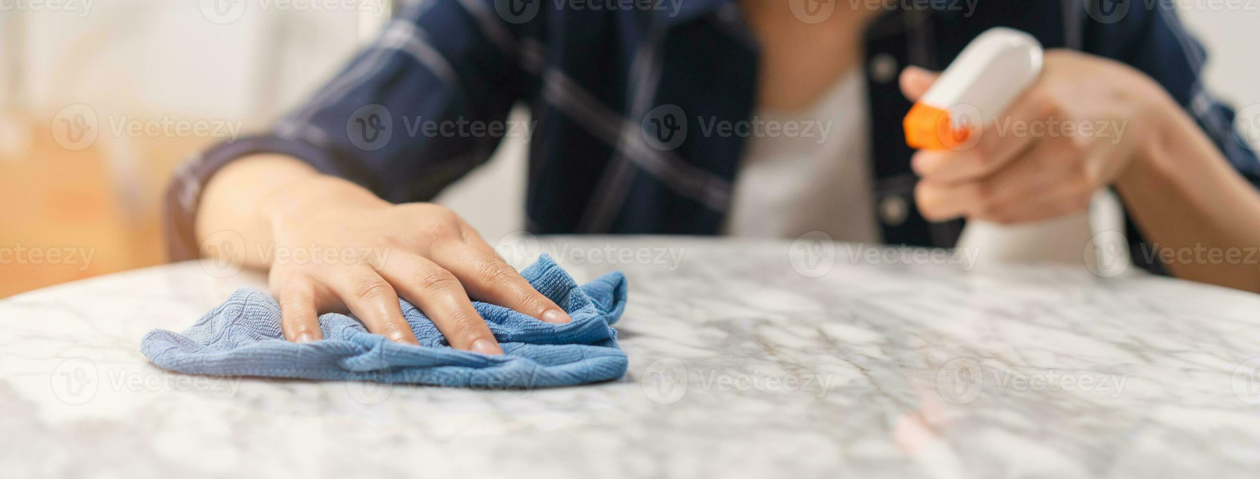 Cleaning hygiene, asian young maid woman, girl hand in using a water sprayer bottle to wipe clean, use blue rag wiping to dust on white marble table in restaurant. Housekeeping cleanup, cleaner. photo