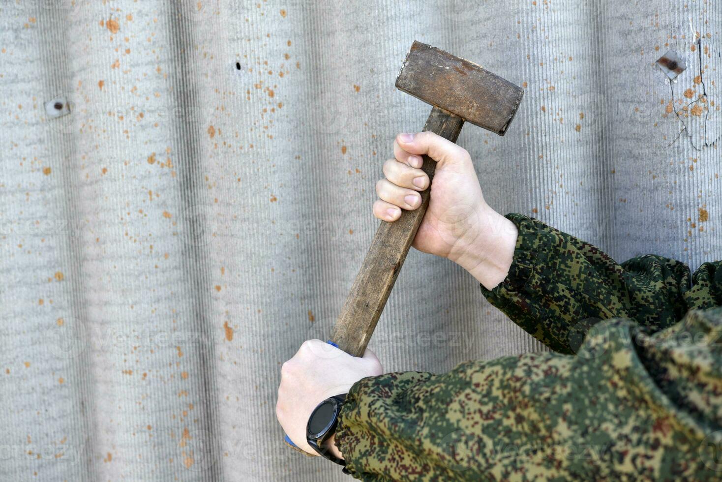 A sledgehammer in the hands of a man. A large hammer in his hands. photo