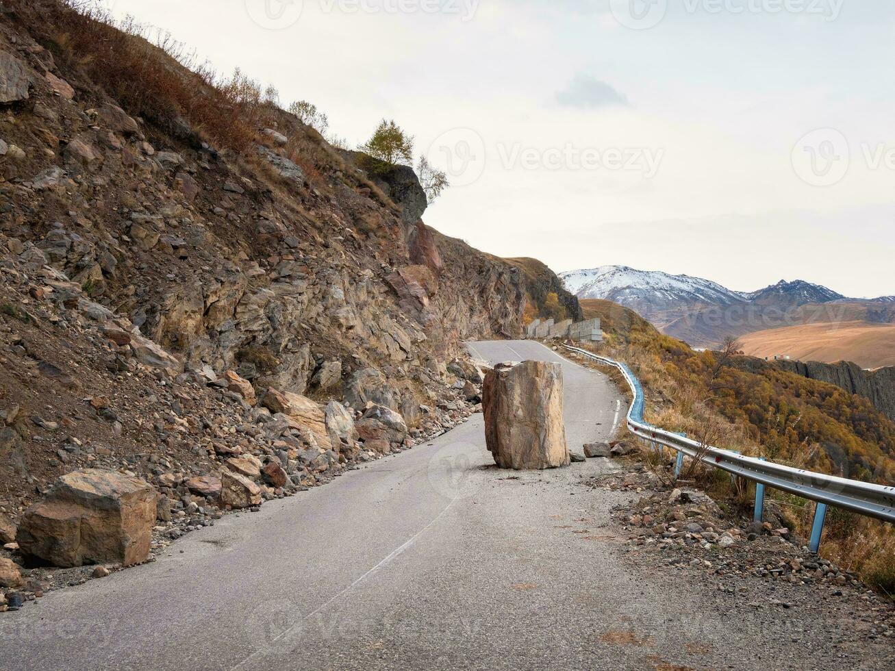 The consequences of an earthquake on a mountain highway. Large granite boulder fell on the road. Dangerous mountain road after earthquake. Dangerous driving on a mountain road during a rockfall. photo