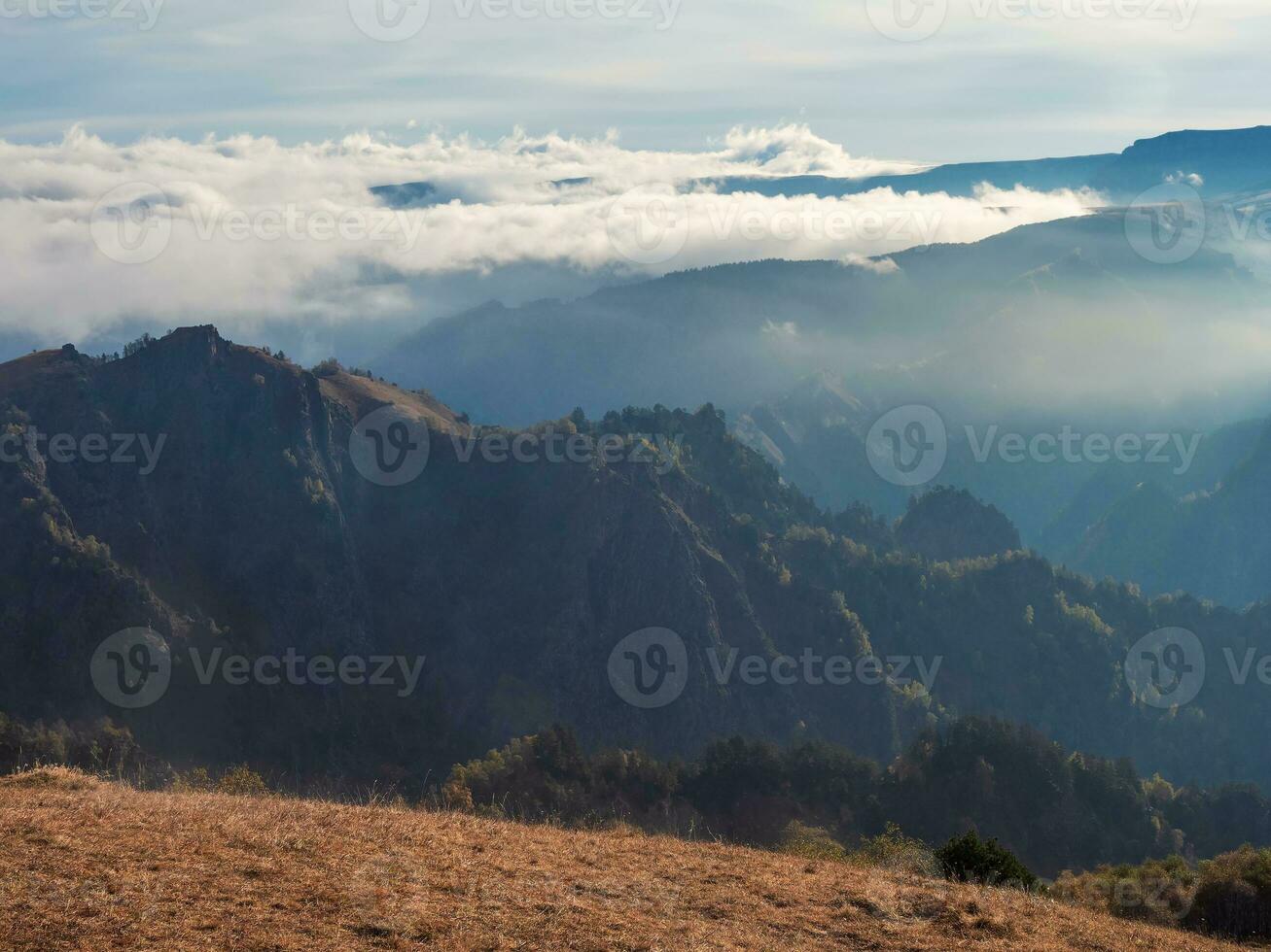 Soft focus. Mountains in a dense fog and sunny slope. Mystical landscape with beautiful sharp rocks in low clouds. Beautiful mountain foggy scenery on abyss edge with sharp forest slopes. Amazing land photo