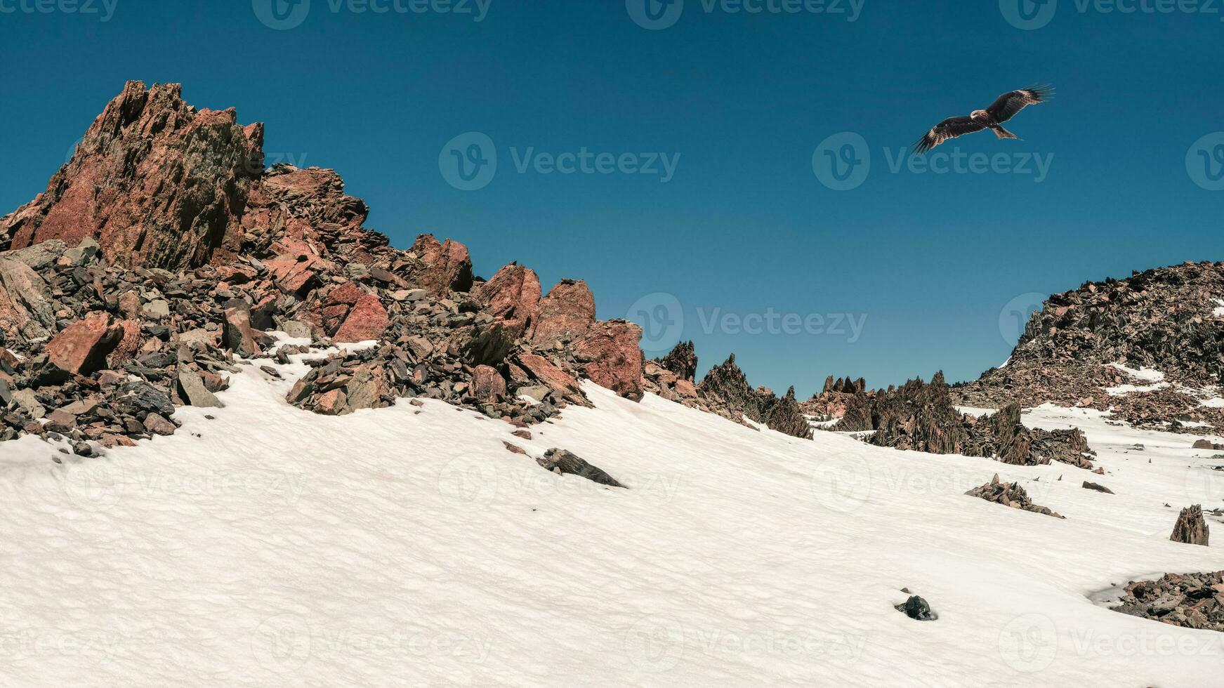 panorámico ver de el agudo rocas cubierto por nieve y hielo. un cometa moscas terminado el montaña. invierno montaña paisaje. foto