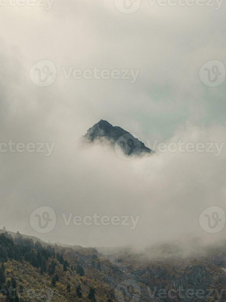 Soft focus. Darkness mountain background. Dramatic fog among giant rocky mountains. Ghostly atmospheric view to big cliff. Low clouds and beautiful rockies. Minimalist scenery mysterious place. photo