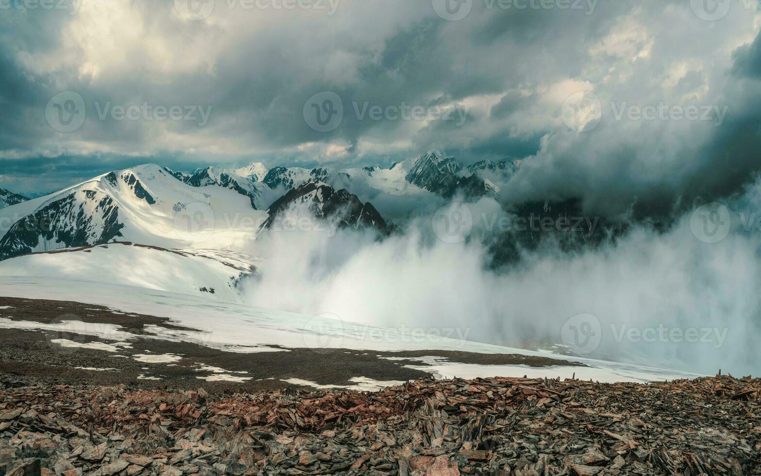 maravilloso dramático paisaje con grande Nevado montaña picos encima bajo nubes atmosférico grande nieve montaña tapas en nublado cielo. foto