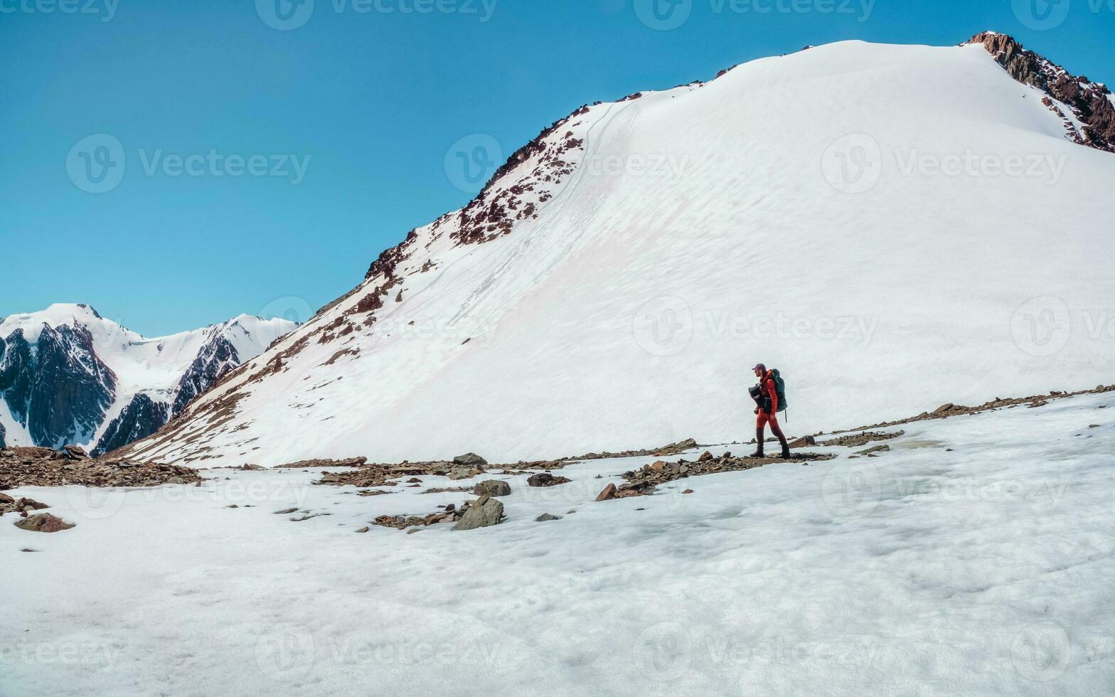 extremo recreación y montaña turismo. un masculino caminantes abajo el montaña camino. en el fondo, grande nevadas montañas. Copiar espacio. foto