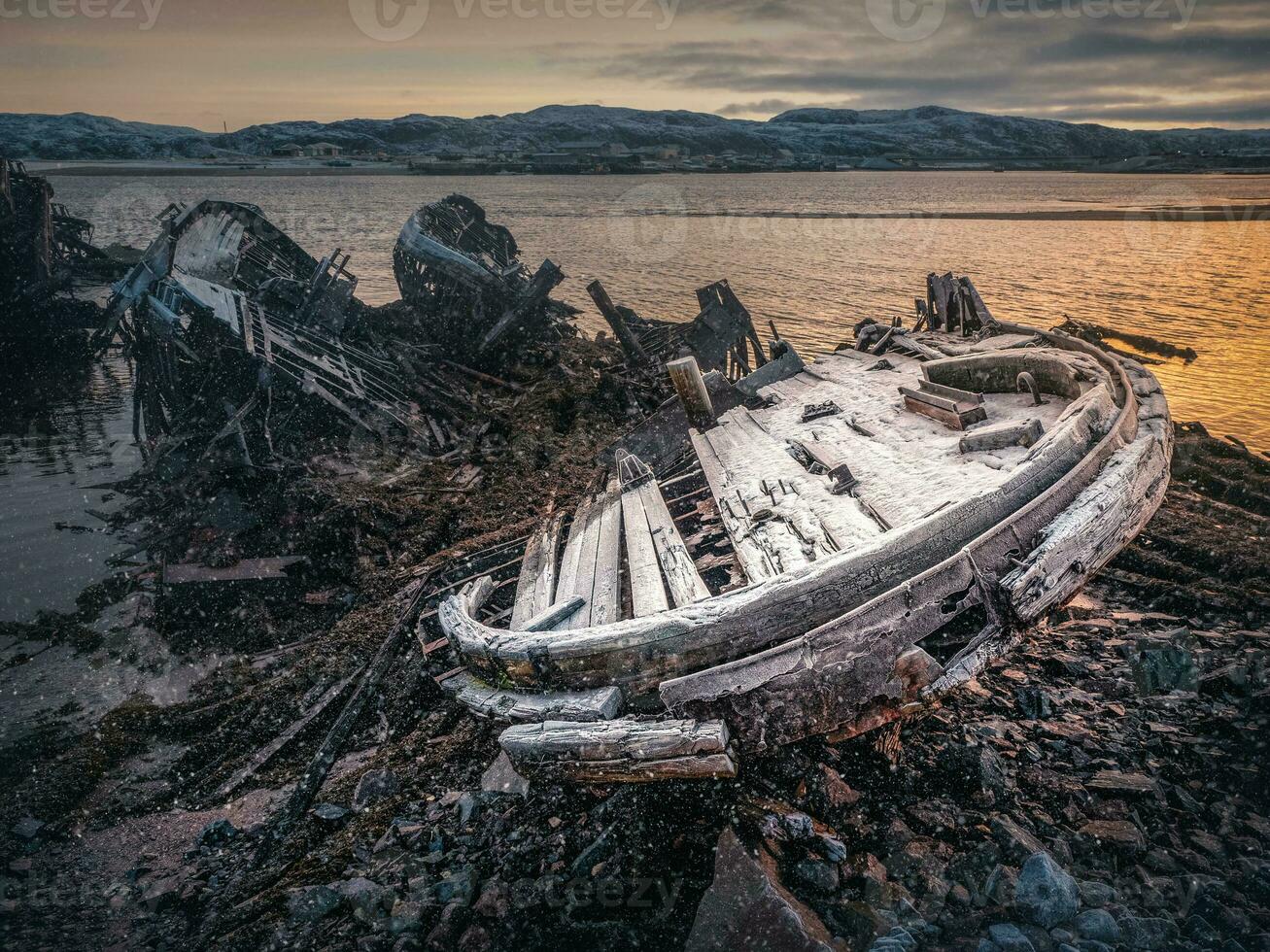 Old rusty fishing boat abandoned by a storm on the winter shore. Graveyard of ships. photo