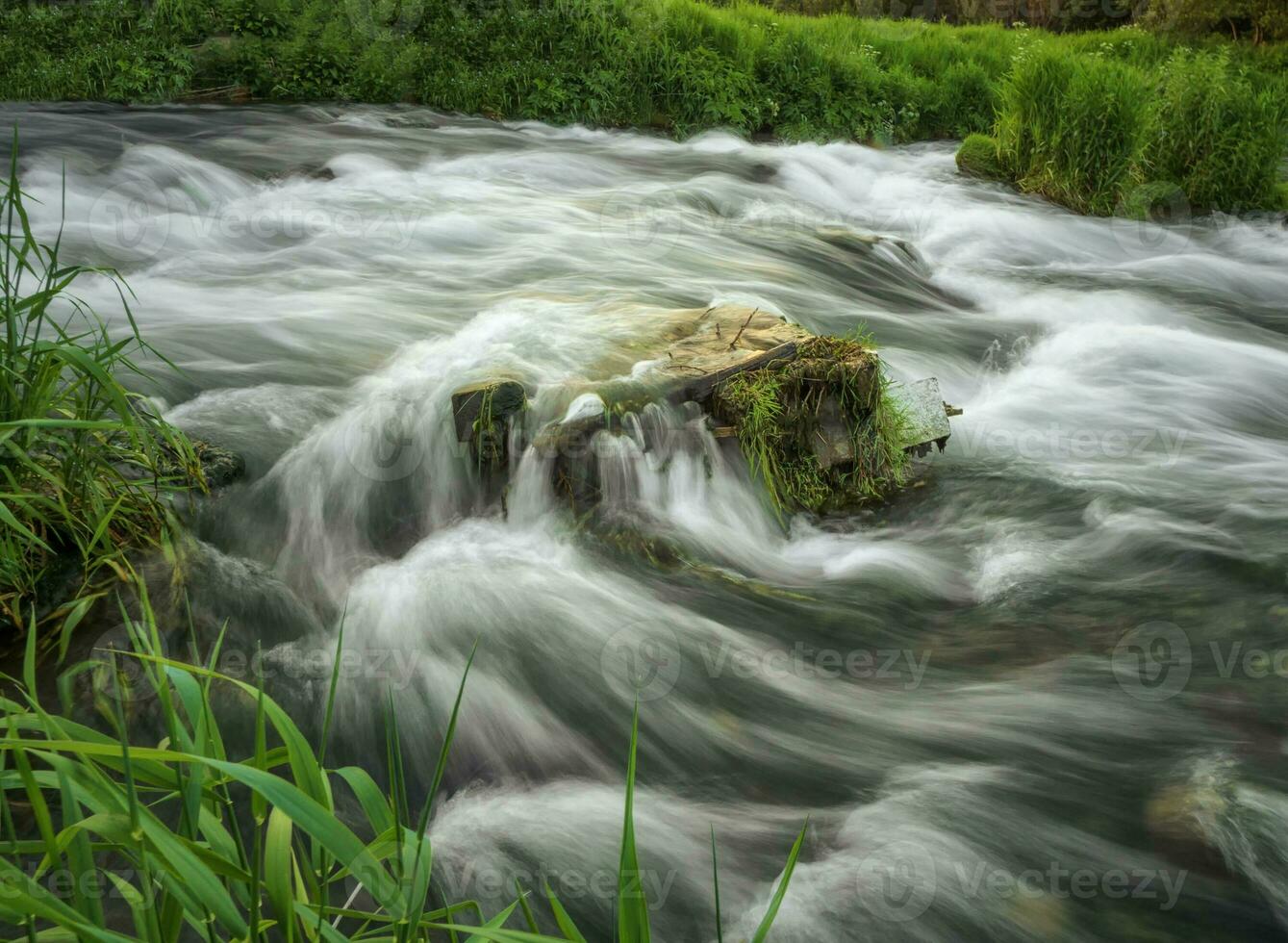 Nature background with boulders in water riffle of mountain river. Powerful water stream of mountain creek. Backdrop of fast flow of mountain brook with rapids photo