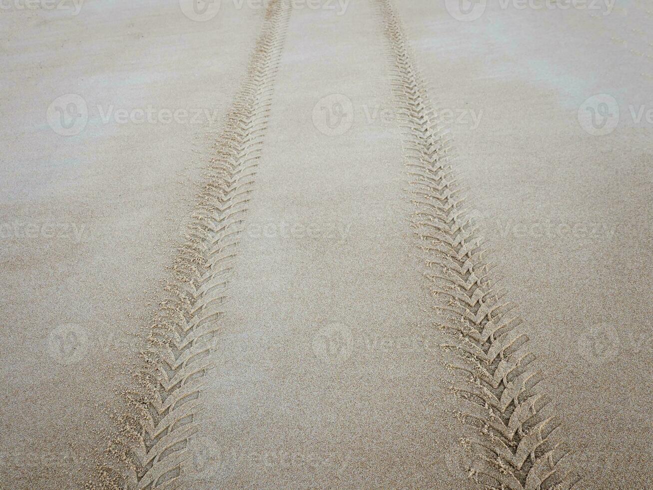 Tire tread mark on the sea sand extending into the distance photo