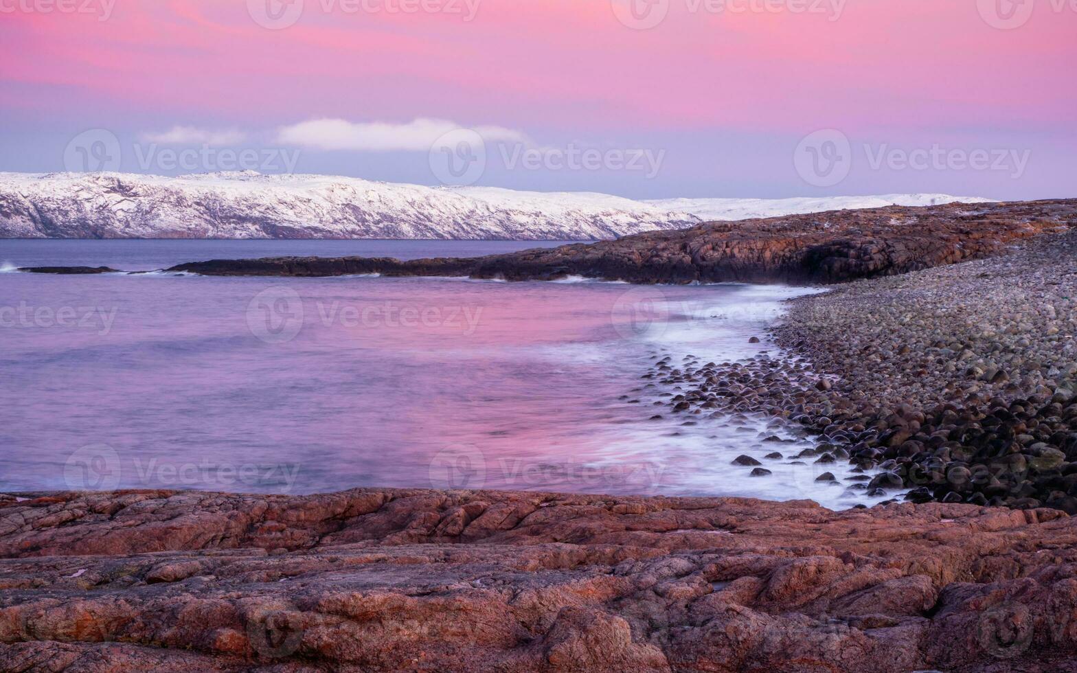 A rock cliff with a tidal shoreline. Wonderful panoramic mountain landscape on the Barents sea. photo