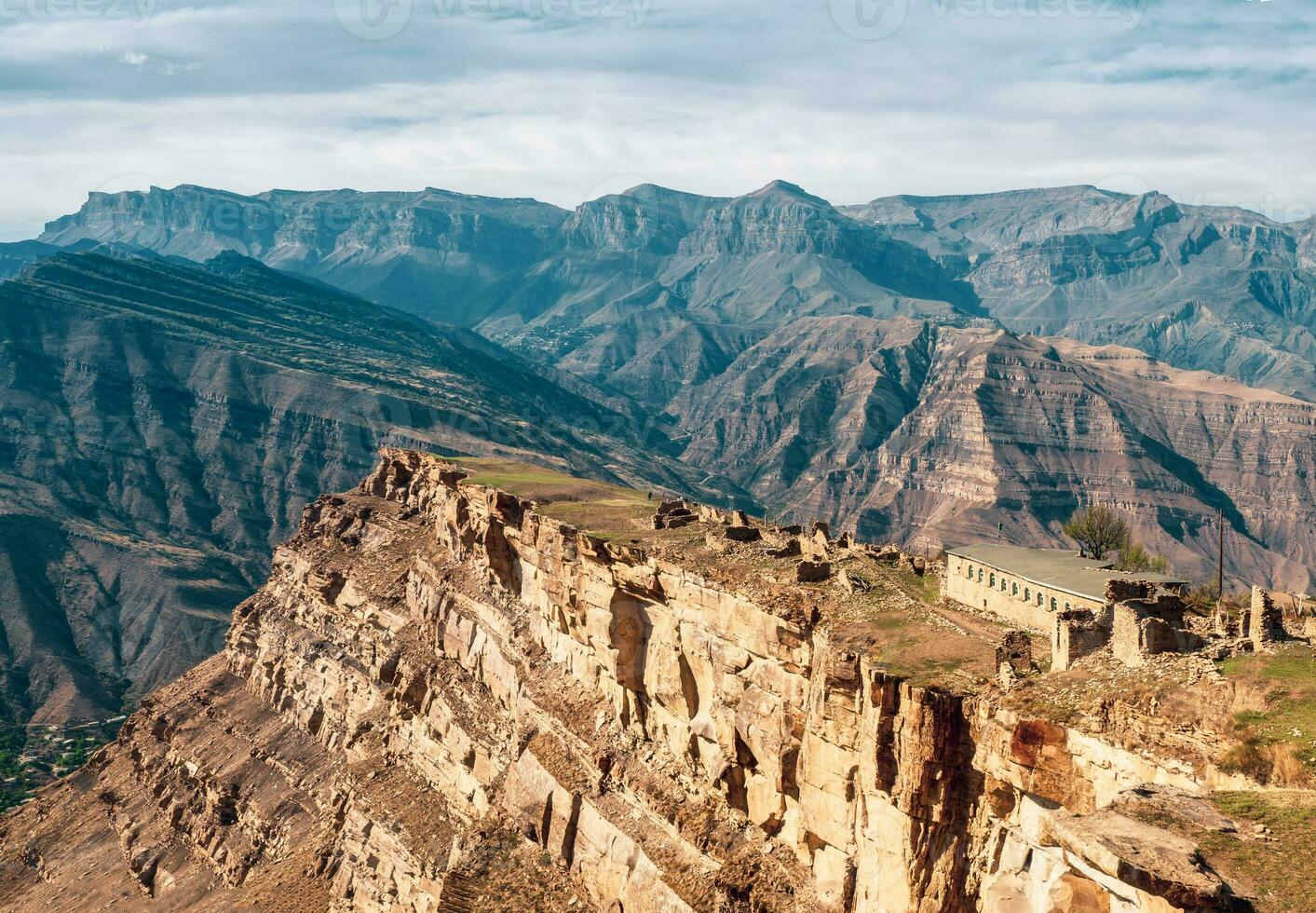 Summer view of ruins in the aul ghost Goor in Dagestan in the evening light. A stone building on a high cliff. photo