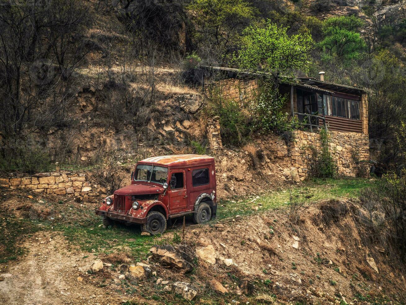 Rusty Gaz-69 car on a slope near a house in a mountain village. Dagestan. photo