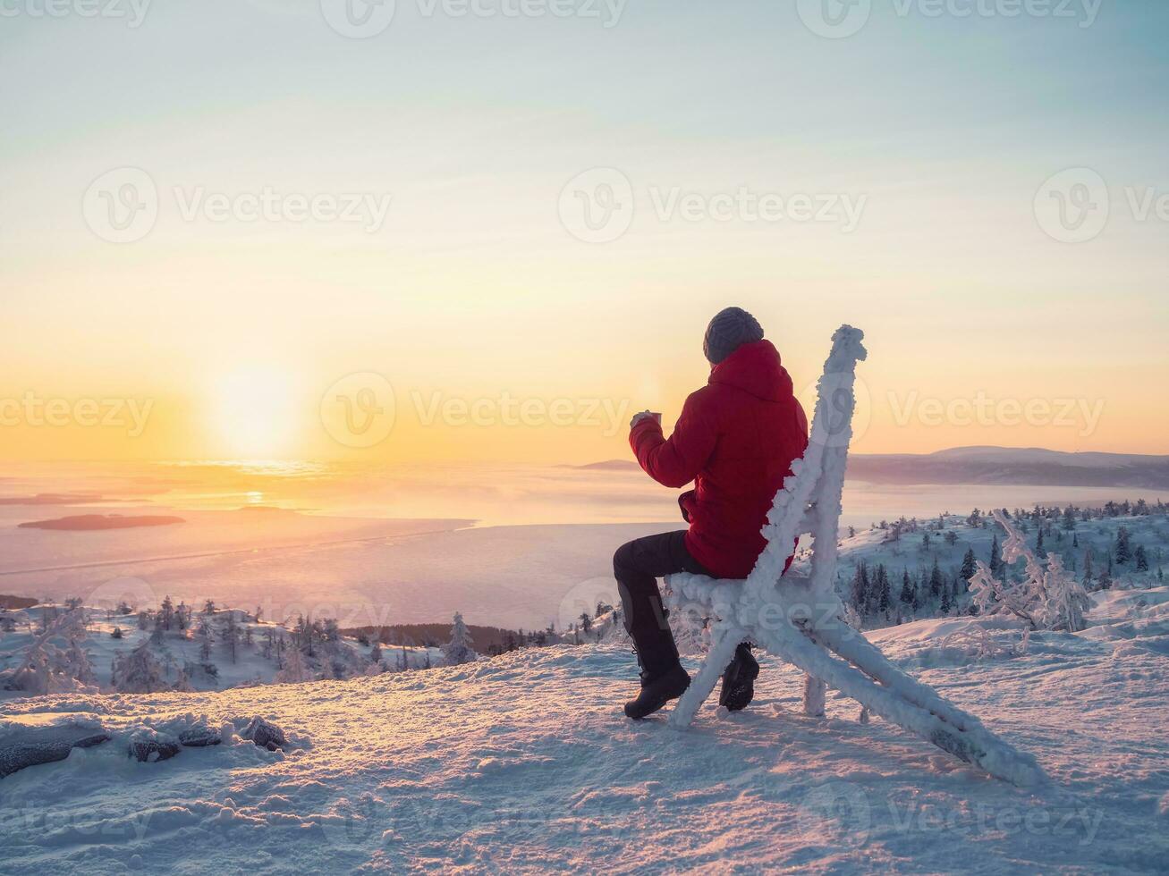 contento hombre con un taza de té a amanecer. ver en el congelado mar desde arriba. café desde el al aire libre. Nevado montaña antecedentes. invierno vacaciones, turismo, viaje y personas concepto. foto