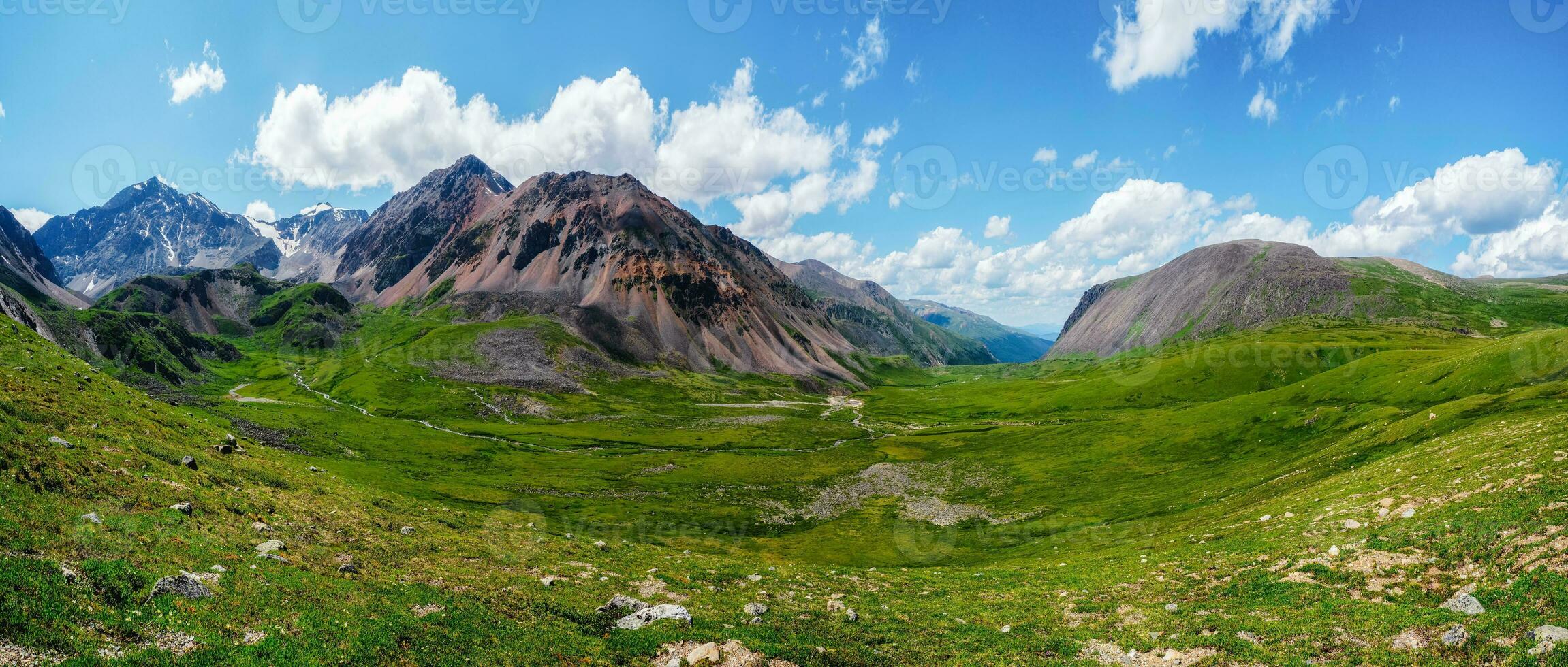 Scenic green blue alpine panoramic landscape with highland valley in sunlight and big glacier under blue cloudy sky. Shadow of clouds on green mountain valley photo