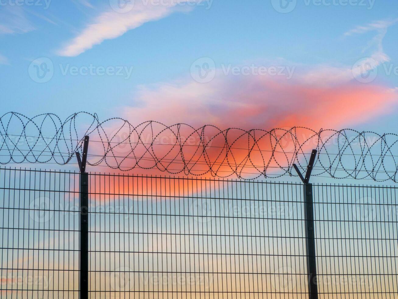 Fence with barbed wire on the background of the Arctic sky. photo