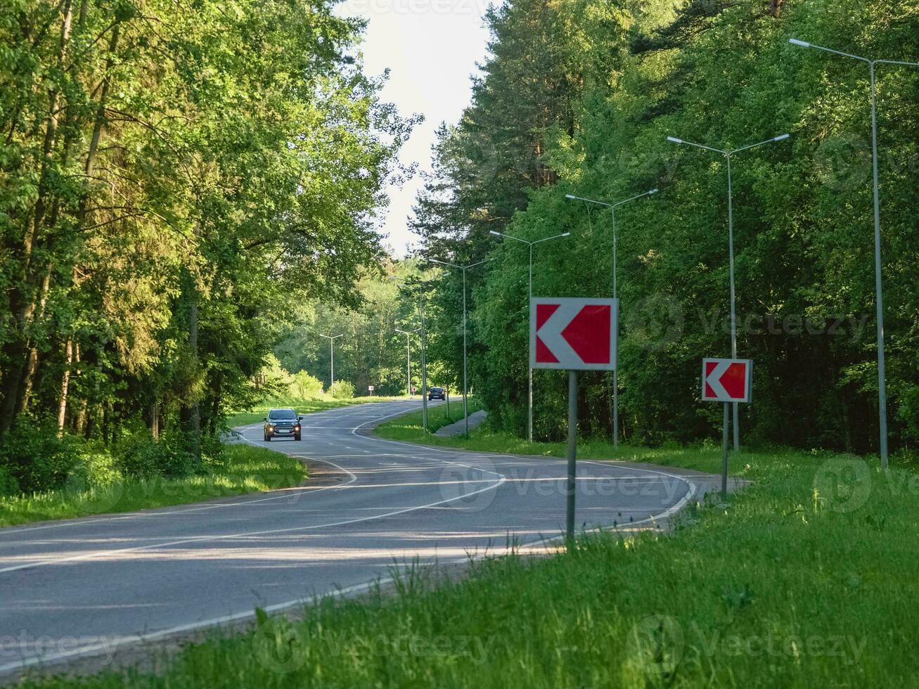 Car rides on winding highway in an summer forest photo