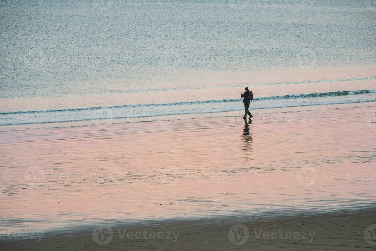 A lone tourist with a backpack shoots a wonderful Arctic sunset landscape on the ocean. photo