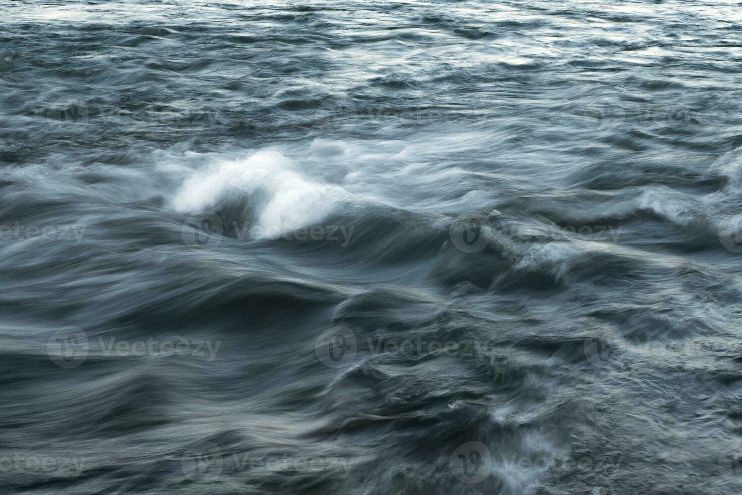 The stream of water, blurred view. Powerful water flow with breakers on the sea photo