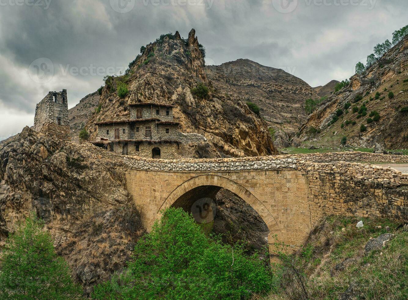 Dramatic mountain scenery with old stone bridge in dark rainy day. photo