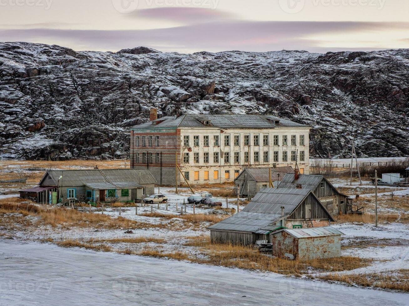 Authentic village of Teriberka in the North of Russia. The building of an old abandoned school against the backdrop of Arctic hills in winter photo