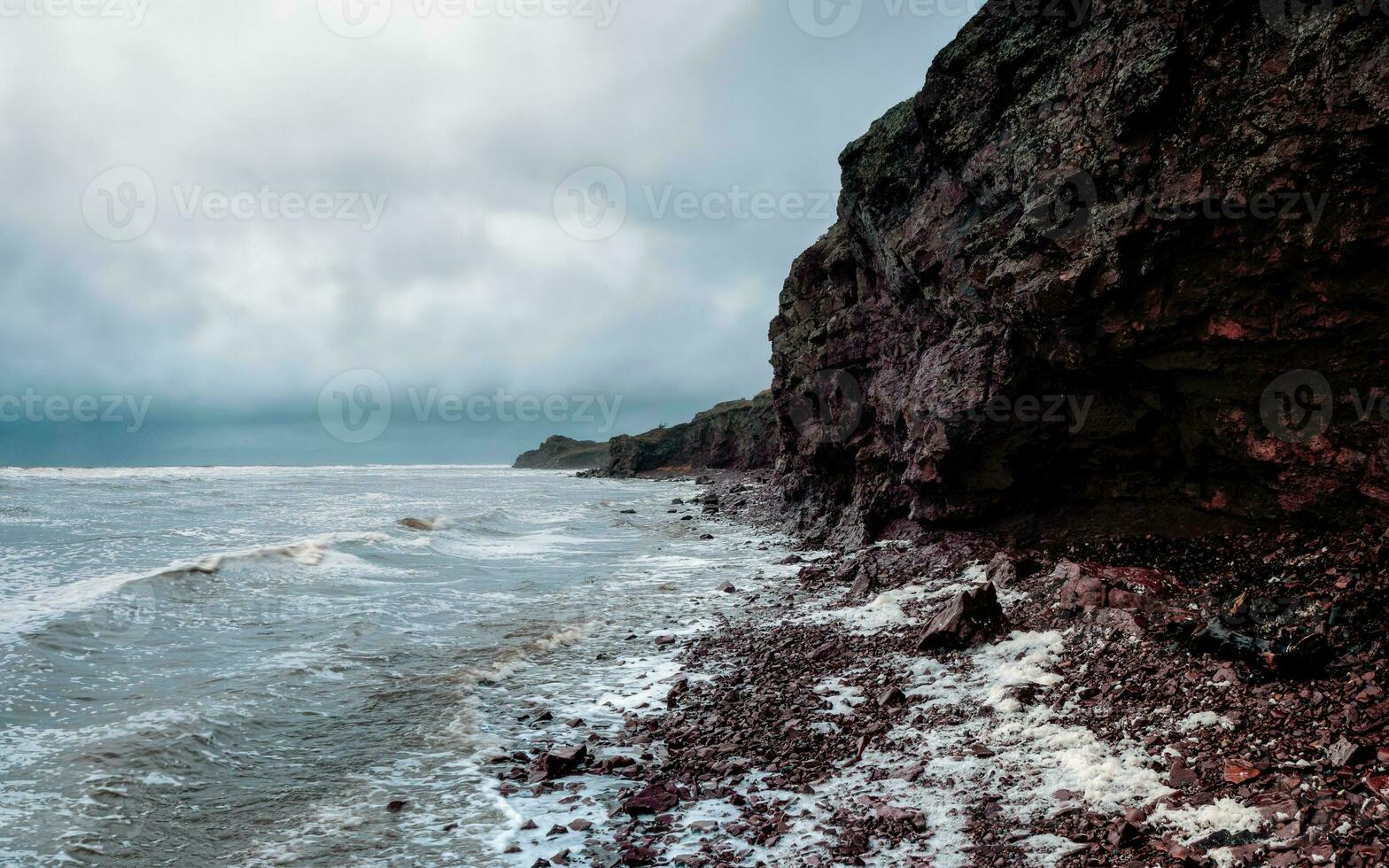 A rock cliff above the water with a tidal shoreline. Tersky coast of the White Sea.. Panoramic view. photo