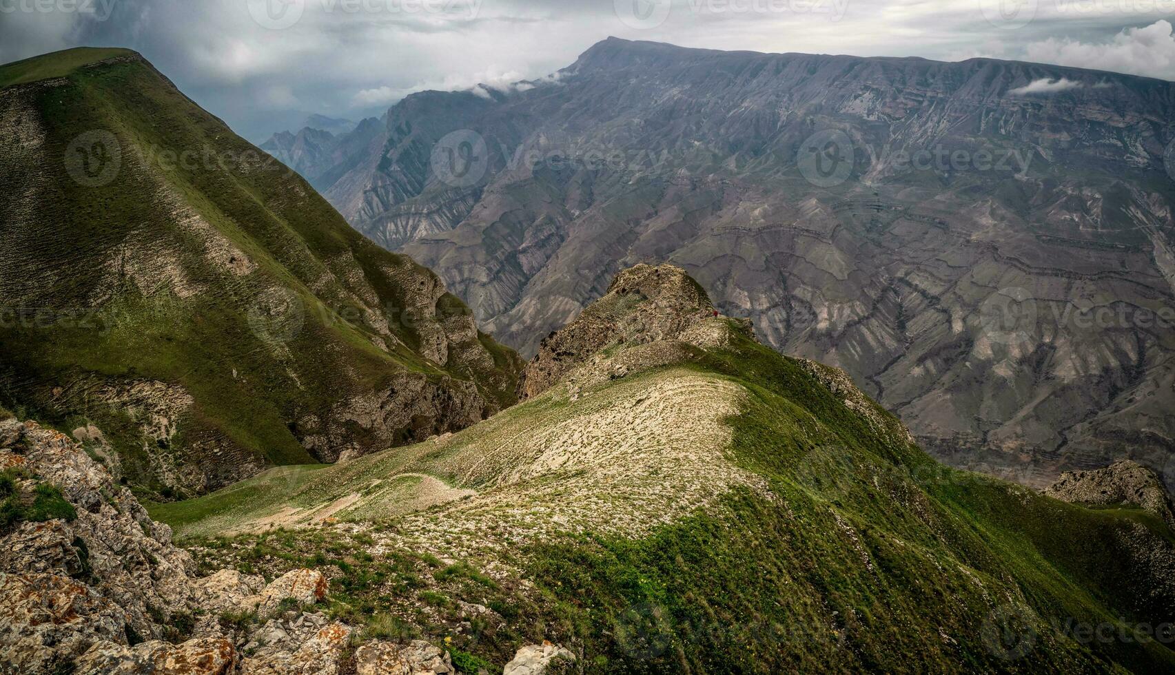 A rocky ledge stretching into the distance against the background of green textured mountains. photo