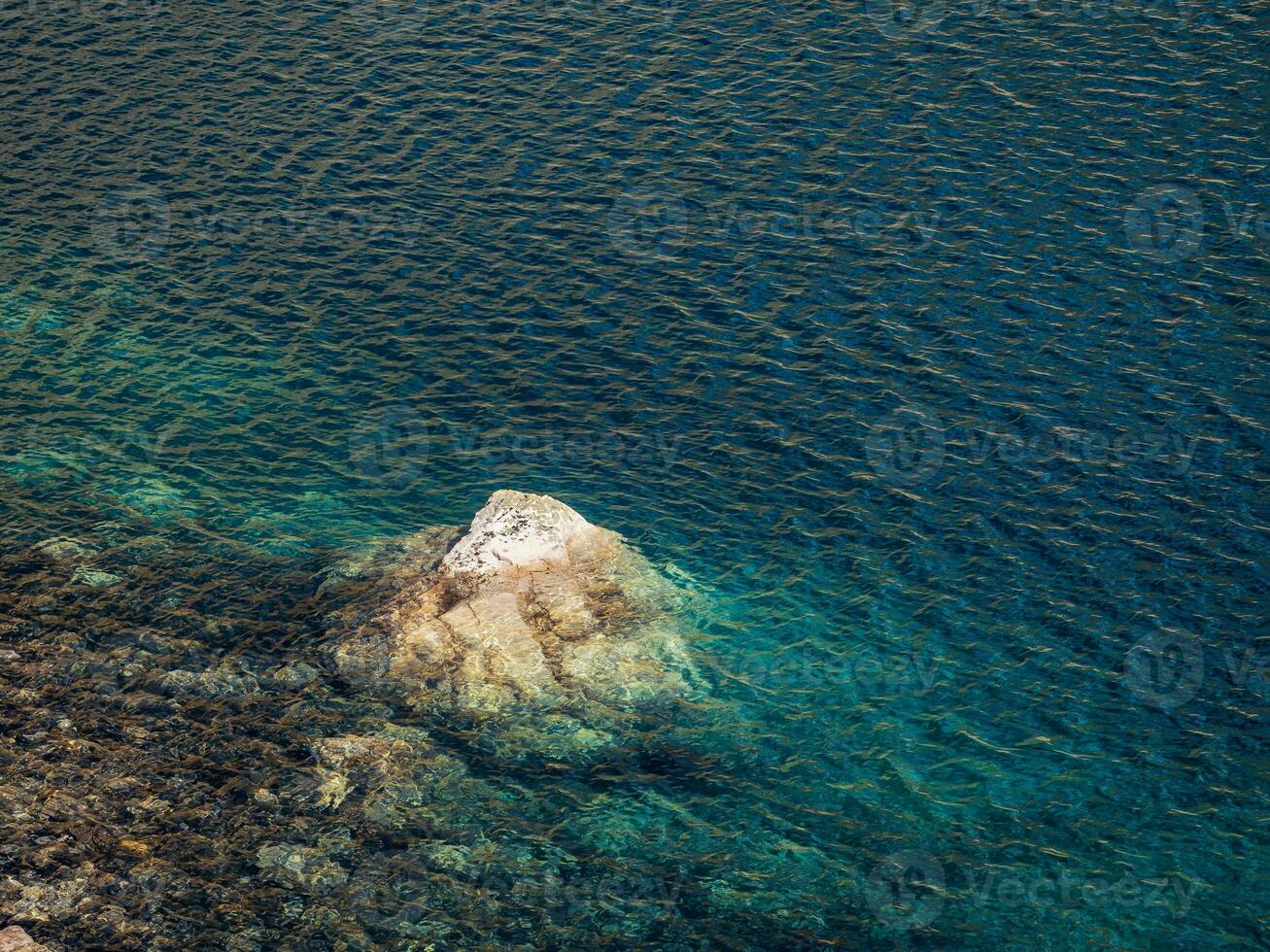 Beautiful nature background of stony bottom in turquoise transparent water of glacial lake in sunlight. Sunny backdrop with many stones in green clear water of glacier lake. photo