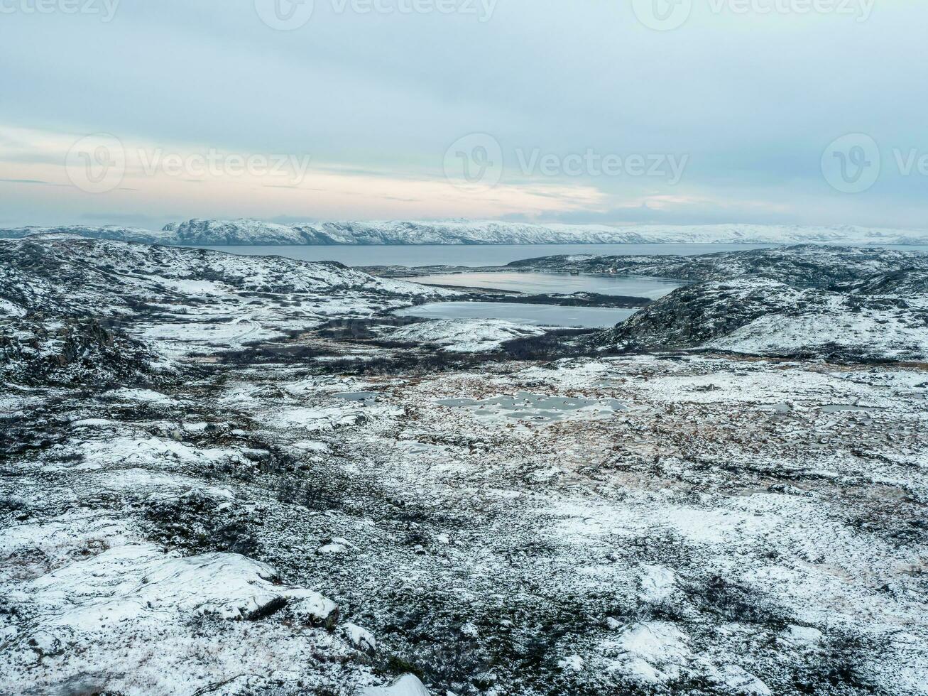 increíble ártico paisaje con un alta altitud congelado lago. ártico tundra antecedentes. nieve Valle con rocas y sierras. puro salvaje naturaleza concepto foto