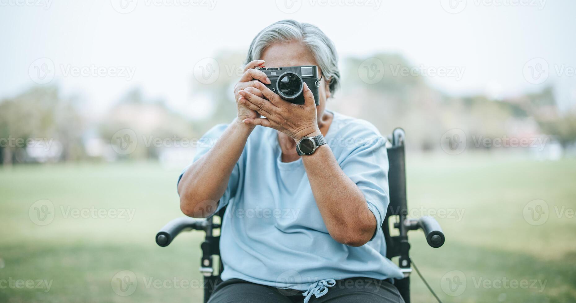 Mature Asian woman on wheelchair use digital camera photo