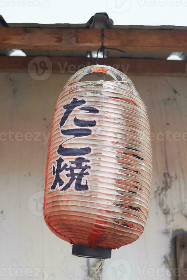 old and torn Traditional Japanese shop sign lantern, hung in front of the store photo